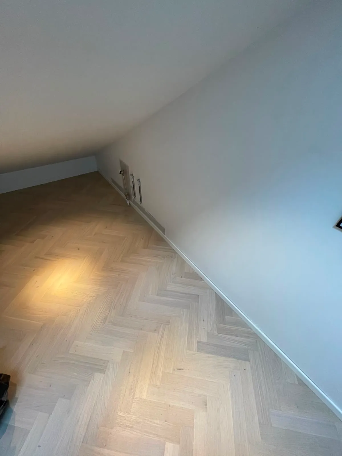 Ljus fiskbensparkett anpassad runt elementrören